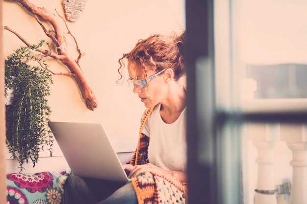 Bureau alternatif pour travailler en plein air à la maison sur la terrasse - belle femme caucasienne concentrée travaillant avec un ordinateur portable - style de filtre de couleurs vintage - concept indépendant