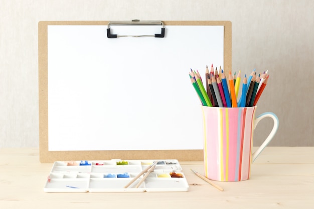 Bureau d’artiste avec planche à dessin, objets de papeterie. Studio tourné sur fond en bois.