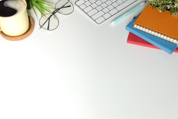 Bureau blanc avec carnet de notes tasse à café et clavier sans fil