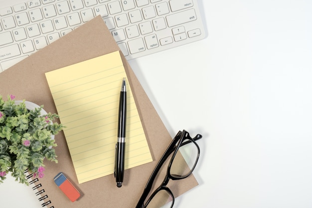 Photo bureau blanc avec le livre d'équipement de bureau, note de papier, clavier et crayon