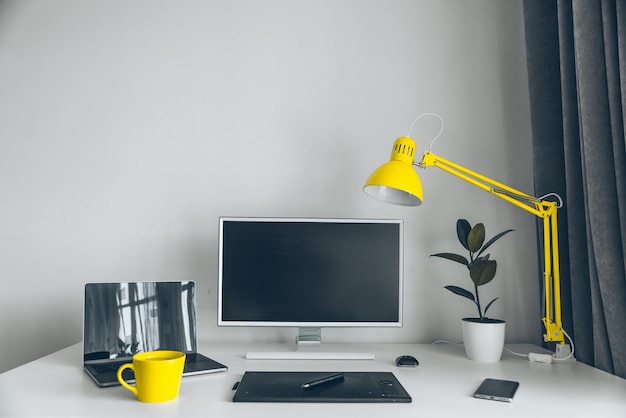 Bureau blanc en milieu de travail avec ordinateur portable et lieu de travail de concepteur de tasse jaune