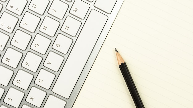 Bureau blanc moderne avec un clavier d'ordinateur, un stylo et un cahier