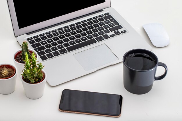 Bureau blanc avec ordinateur portable, smartphone et autres fournitures de travail avec une tasse de café Espace de travail de concepteur sur les éléments essentiels de la table de bureau à plat