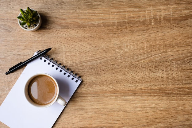 Bureau avec bloc-notes vierge et tasse de café sur une table en bois