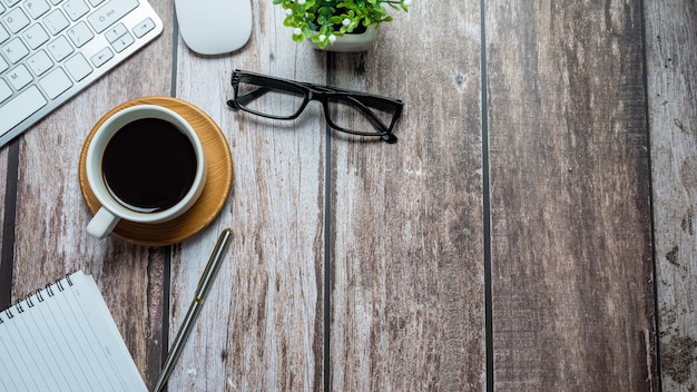 Sur un bureau en bois avec café, lunettes, clavier, ordinateur portable, espace de copie de pâte plate.