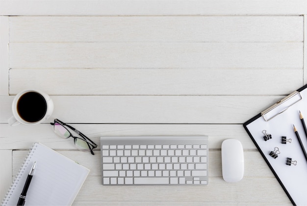 Photo bureau en bois plat lapointe, vue de dessus. espace de travail avec presse-papiers vierge, clavier, ordinateur souris, lunettes, fournitures de bureau tasse à café avec espace coppy sur fond de table en bois blanc