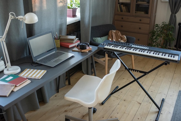 Bureau de clavier de piano avec ordinateur portable et fauteuil dans le salon