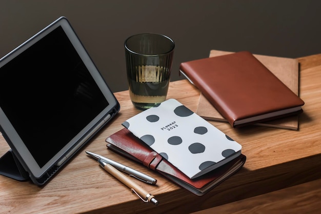 Bureau à domicile Une tablette un planificateur un carnet de notes et un verre d'eau sur une table en bois dans le salon