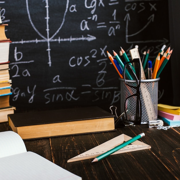 Bureau d&#39;école dans la salle de classe, avec des livres sur fond de tableau avec des formules écrites