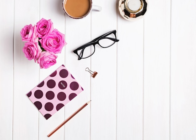 Bureau élégant. Café, fleurs, verres et autres accessoires sur fond blanc