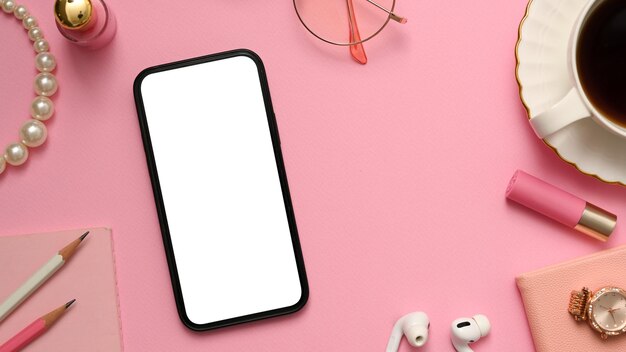 Bureau féminin avec maquette d'écran blanc de smartphone sur la vue de dessus de fond rose