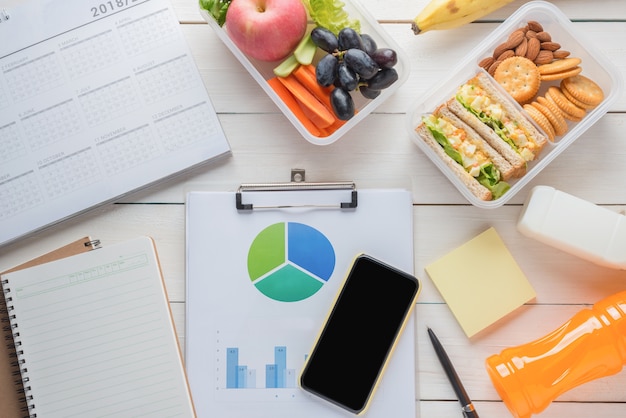Bureau avec des fournitures, salade d'oeufs avec une tranche de sandwich dans la boîte à lunch