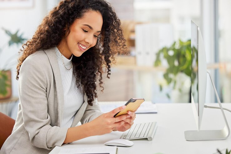 Photo bureau de frappe et femme au bureau avec réseau téléphonique et connectivité avec chat en ligne smartphone médias sociaux et consultant heureux avec application mobile pour une planification facile du calendrier dans les entreprises en démarrage