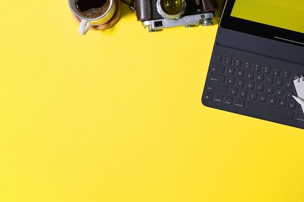 Bureau jaune créatif vue de dessus avec tablette, appareil photo vintage et espace de copie