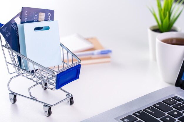 Bureau en ligne payant séjour à domicile shopping paiement électronique avec concept de carte de crédit ordinateur portable sur fond de tableau blanc avec panier de magasin en gros plan