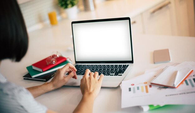 Bureau à la maison Freelancer Jolie jeune femme moderne en vêtements décontractés à l'aide d'un ordinateur portable tout en travaillant dans la chambre domestique