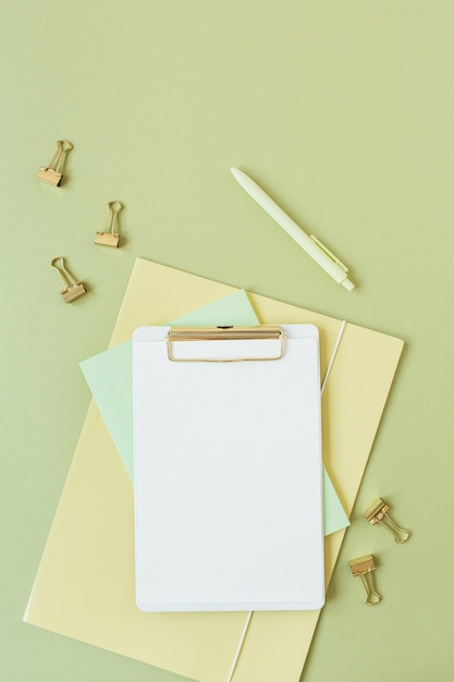 Bureau à la maison minimaliste plat laïque avec presse-papiers de feuille vierge avec espace de copie pour le texte, stylo, clips sur vert
