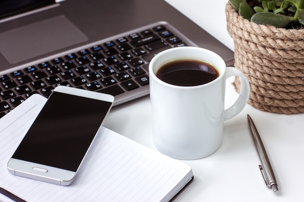 Bureau à la maison pour ordinateur portable ouvert le bloc-notes avec une tasse de café stylo sur tableau blanc