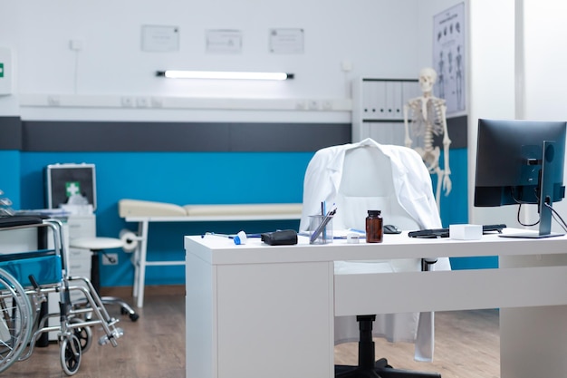 Bureau médical vide équipé de matériel de soins de santé prêt pour l'examen clinique. Lieu de travail hospitalier sans personne ayant des documents sur la maladie sur la table. Service de médecine