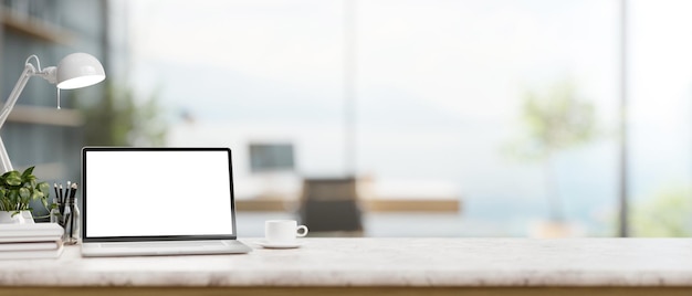 Un bureau minimaliste moderne avec une maquette d'ordinateur portable et un décor sur une table en marbre blanc