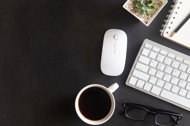 Bureau noir avec ordinateur portable, smartphone et autres fournitures de travail avec une tasse de café. Vue de dessus avec espace de copie pour la saisie du texte. Espace de travail design sur les éléments essentiels de la table de bureau à plat.