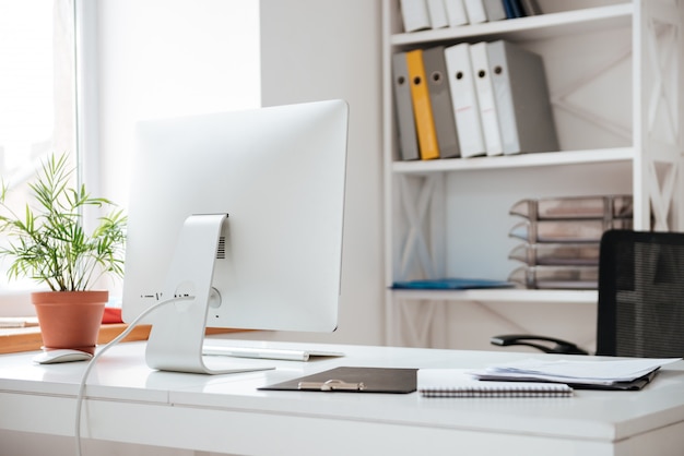 Bureau avec ordinateur et papiers sur table.