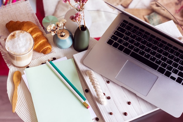 Bureau avec ordinateur portable, café et croissant