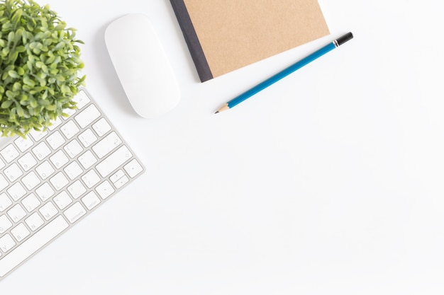 bureau avec souris et clavier, fond blanc avec un crayon