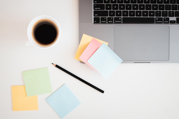 Bureau avec sticky noteordinateur portable crayon et tasse de café sur fond de table en bois blanc