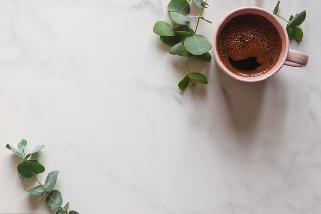 Bureau de table minimal en marbre avec feuilles d'eucalyptus et tasse de café avec espace de copie