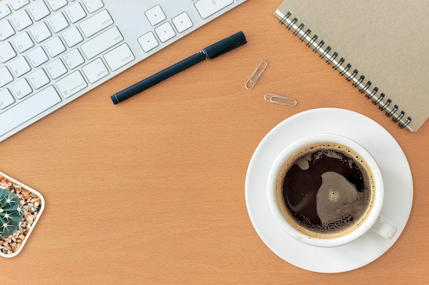 Bureau de travail avec clavier bloc-notes souris café de tasse sur la table en bois. à la lumière