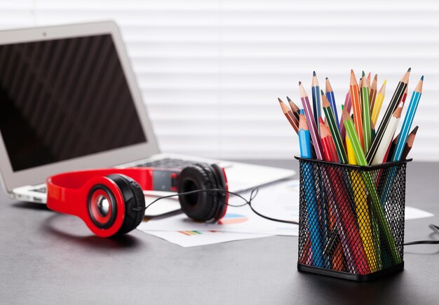 Bureau de travail avec des écouteurs et des crayons pour ordinateur portable
