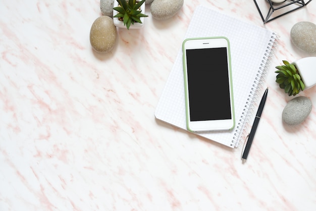 Bureau de travail en marbre avec téléphone, pierres et plantes succulentes