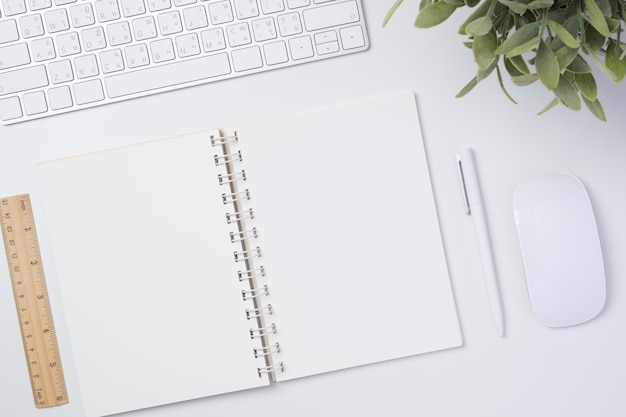 Bureau de travail vue de dessus avec souris clavier et ordinateur portable sur fond de tableau blanc