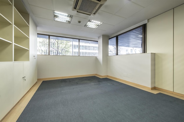 Un bureau vide avec une moquette bicolore un espace avec des cloisons et des classeurs dans la longueur et des plafonds techniques