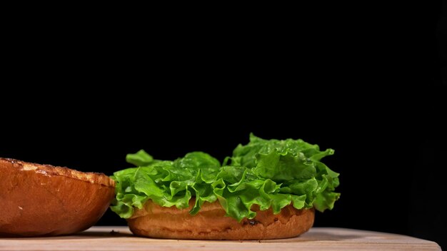 Burger artisanal cuisine sur fond noir dans des gants alimentaires noirs composés de sauce laitue tomate rouge