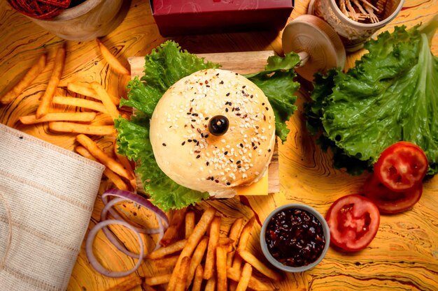Burger au fromage de boeuf barbecue avec frites pomme de terre et tranche de tomate isolé sur planche de bois vue de dessus sur table restauration rapide