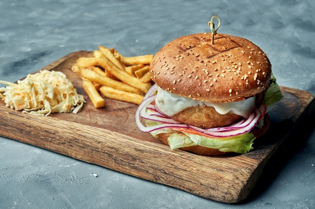 Burger au poulet, fromage, oignon, laitue et tomate sur fond gris