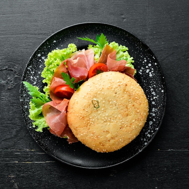 Burger au prosciutto sur fond de bois ancien Petit-déjeuner Vue de dessus Espace libre pour votre texte