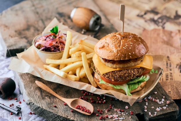 Burger au sésame avec ananas, fromage et frites sur une planche à découper en bois.