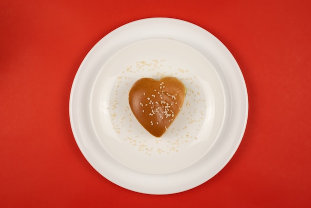 Burger au sésame en forme de coeur sur une plaque blanche