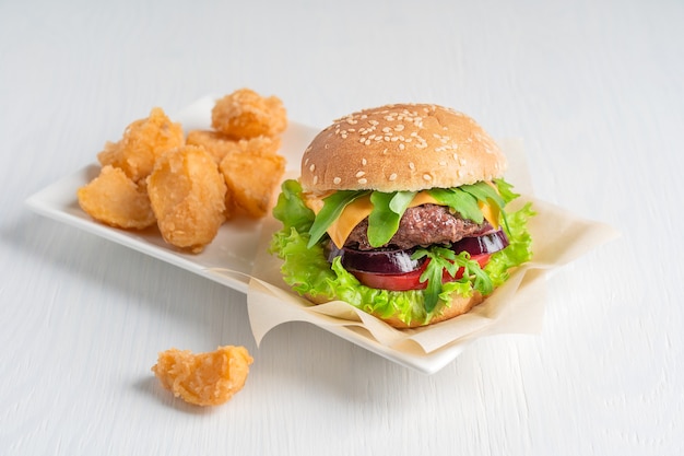 Burger bio juteux à base de laitue au fromage de viande à l'intérieur d'un petit pain au sésame servi avec des quartiers de pommes de terre