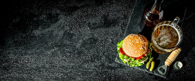 Burger de boeuf et bière dans un verre et une bouteille