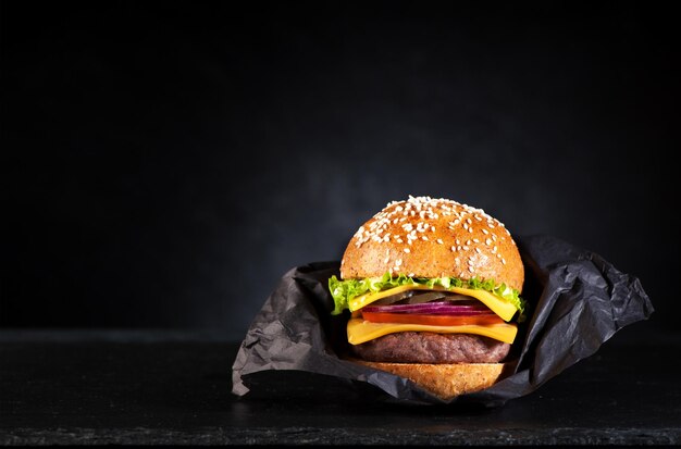 Burger de boeuf dans un papier sur un tableau noir