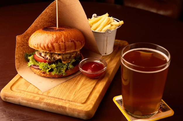 Burger de boeuf frais et savoureux avec frites et bière sur une table en bois au pub