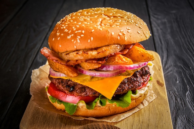 Burger de boeuf avec fromage fondu et bacon sur fond de bois.