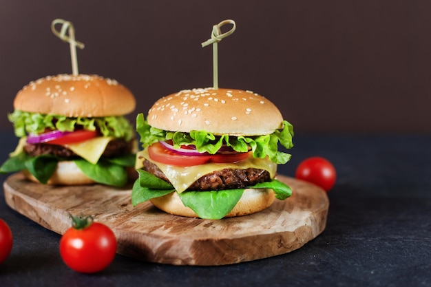 Burger de boeuf avec fromage salade fraîche et tomates sur fond sombre