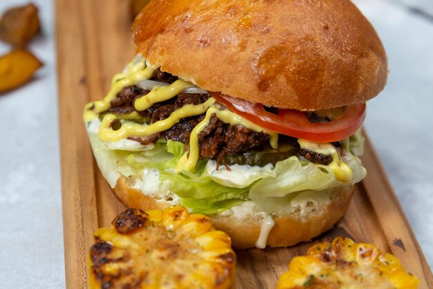 burger de boeuf juteux sur une planche de bois avec du maïs frit