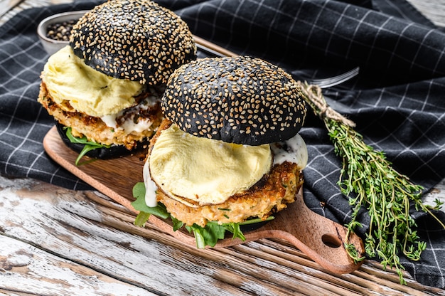 Burger Avec Brioche Au Pain Noir, œufs Brouillés, Galette De Bœuf Et Roquette. Fond Blanc. Vue De Dessus.