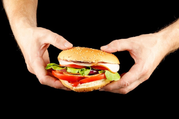 Burger dans les mains isoler sur fond noir